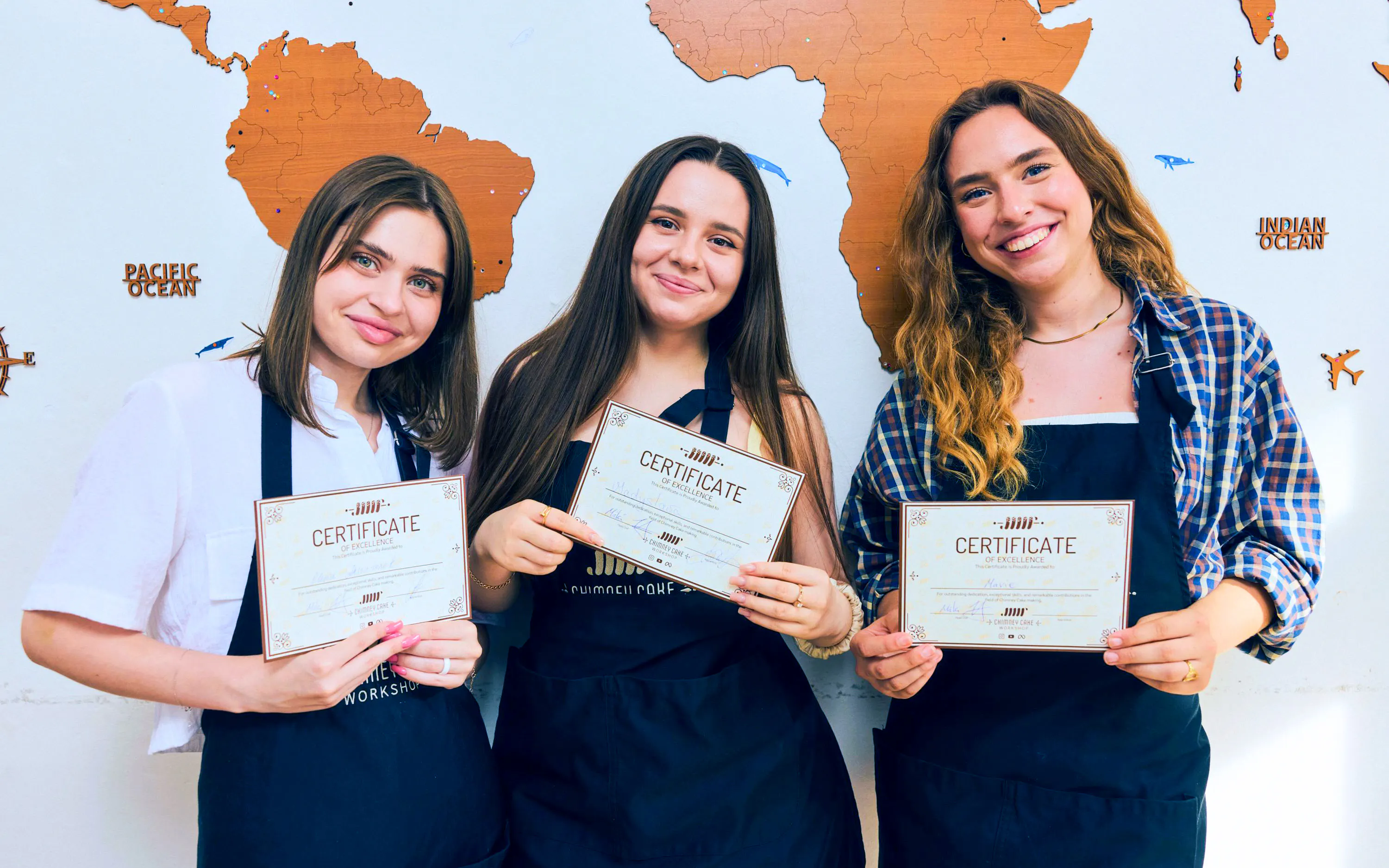 Participants holding certificates at Traditional Chimney Cake Workshop, Budapest.