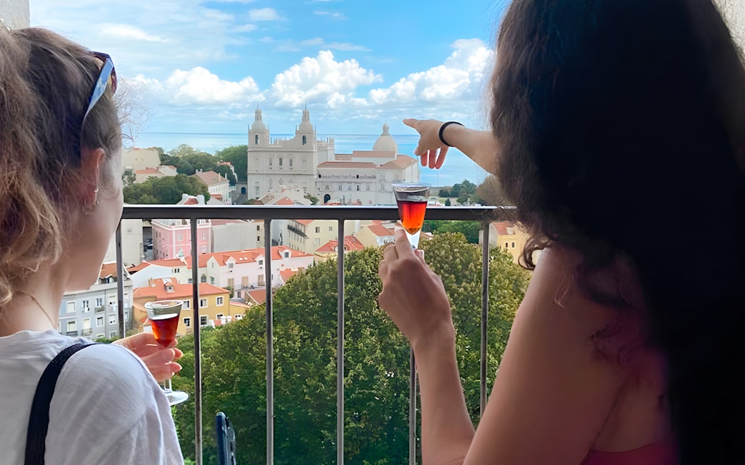 Women enjoying drinks with a view of São Jorge Castle Church in Lisbon.