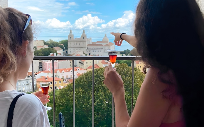 Women enjoying drinks with a view of São Jorge Castle Church in Lisbon.