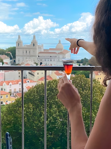 Women enjoying drinks with a view of São Jorge Castle Church in Lisbon.