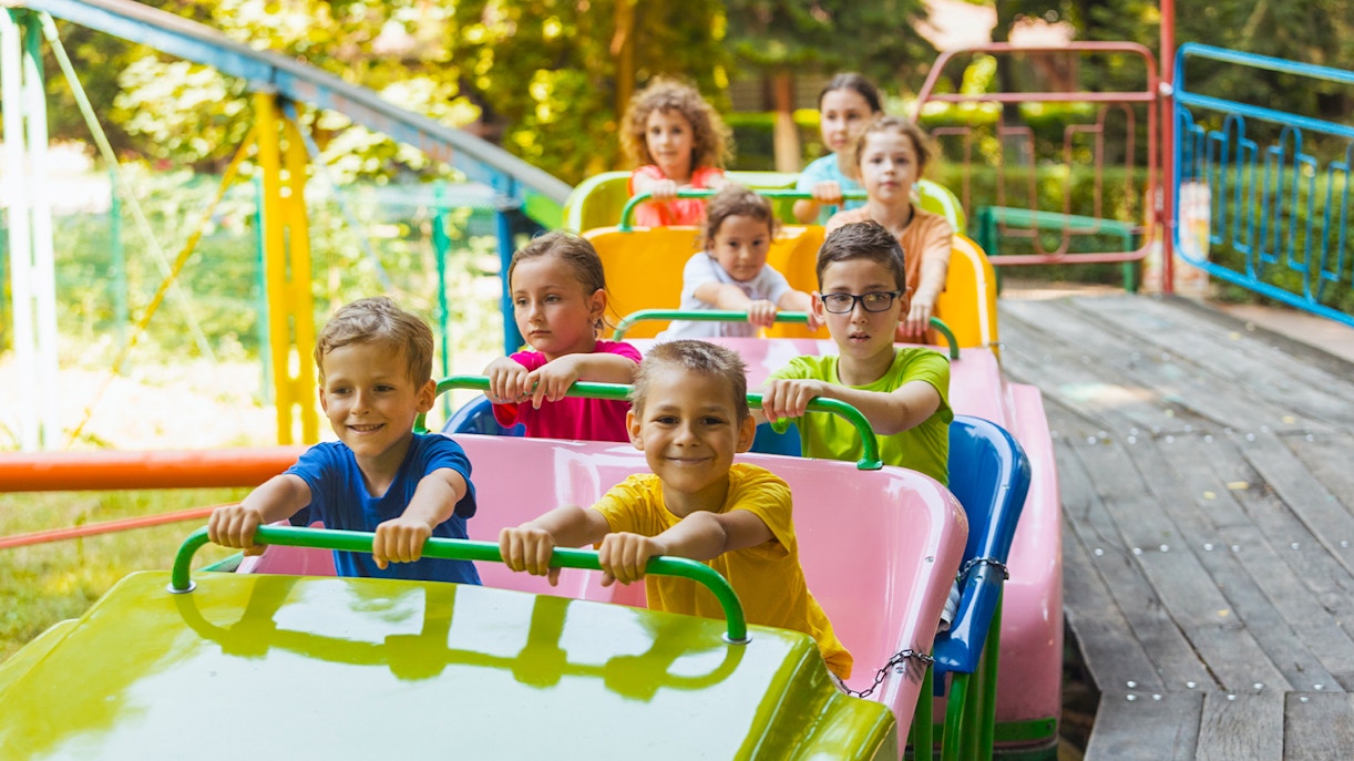 Kids enjoying a colorful roller coaster ride at an amusement park.