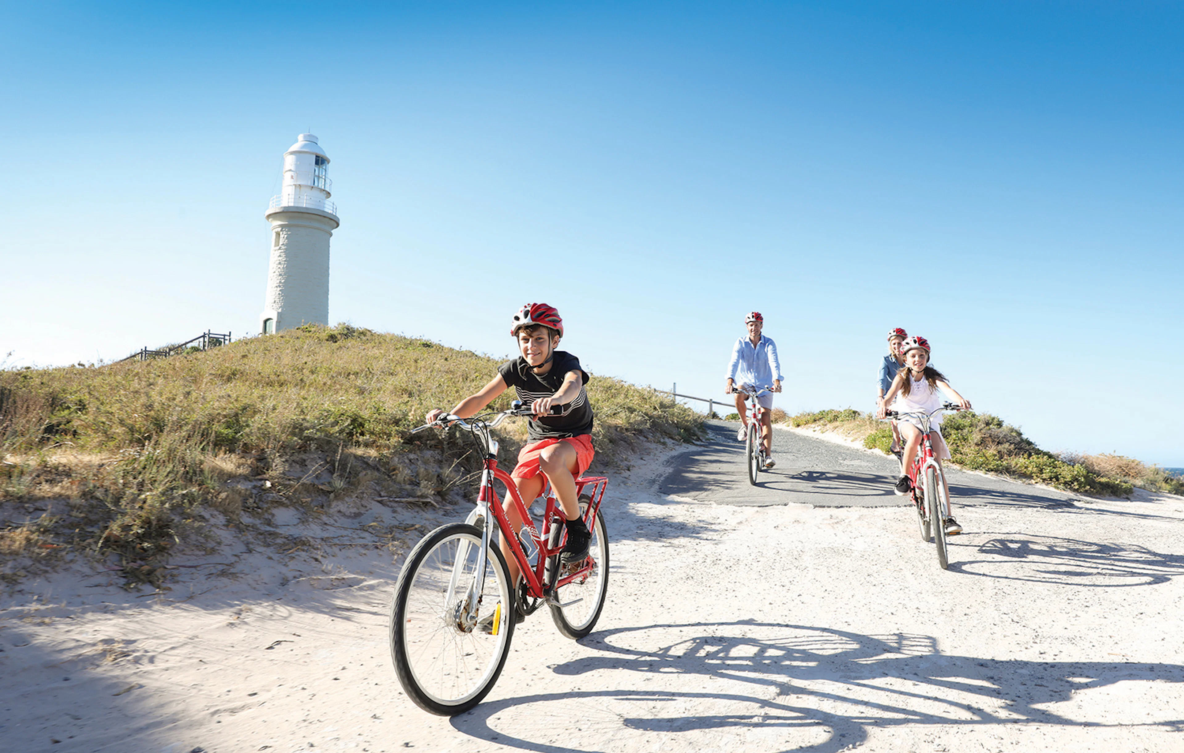 Group cycling towards Wadjemup Lighthouse on Rottnest Island, Western Australia.