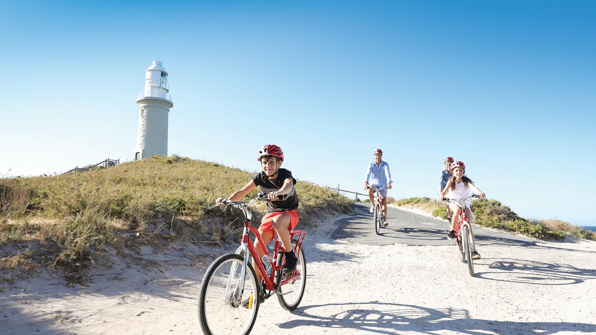 Group cycling towards Wadjemup Lighthouse on Rottnest Island, Western Australia.