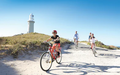 Group cycling towards Wadjemup Lighthouse on Rottnest Island, Western Australia.