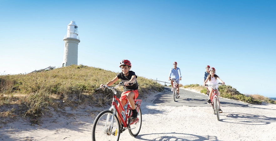 Group cycling towards Wadjemup Lighthouse on Rottnest Island, Western Australia.