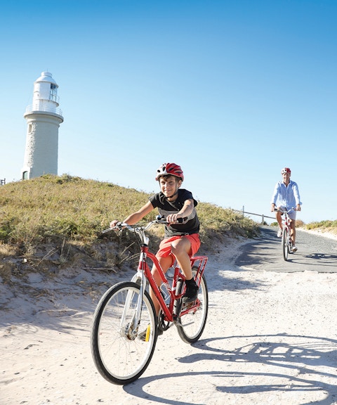 Group cycling towards Wadjemup Lighthouse on Rottnest Island, Western Australia.