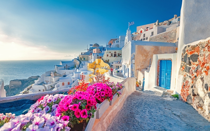 Oia village in Santorini with colorful flowers and whitewashed buildings in spring.
