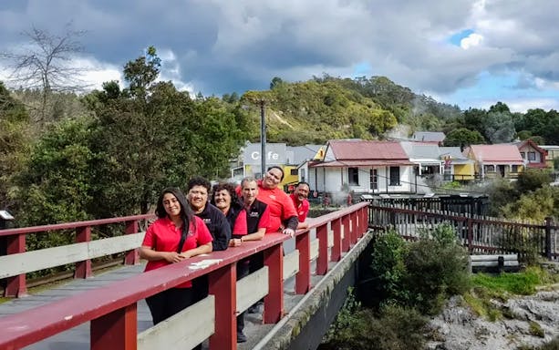 Group on a bridge during a cultural performance tour in a scenic village setting.