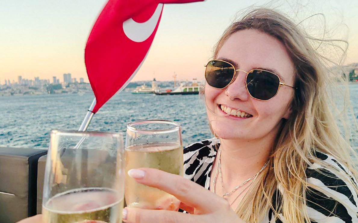 Toasting with drinks on a Bosphorus private luxury yacht, Istanbul skyline in background.