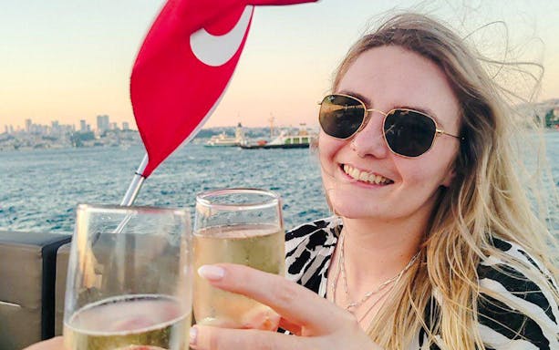 Toasting with drinks on a Bosphorus private luxury yacht, Istanbul skyline in background.