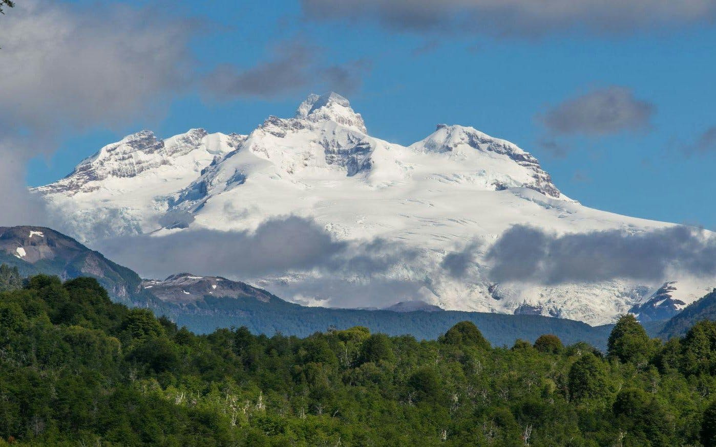 Mount Tronador with snow-capped peaks above Patagonian forest.