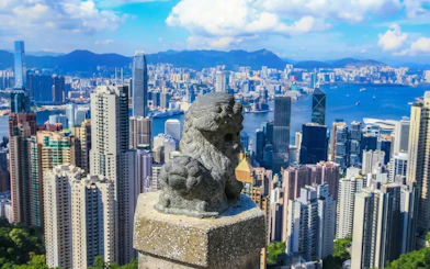 Lion statue overlooking Hong Kong skyline from The Peak Tram viewpoint.