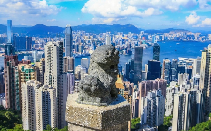 Lion statue overlooking Hong Kong skyline from The Peak Tram viewpoint.
