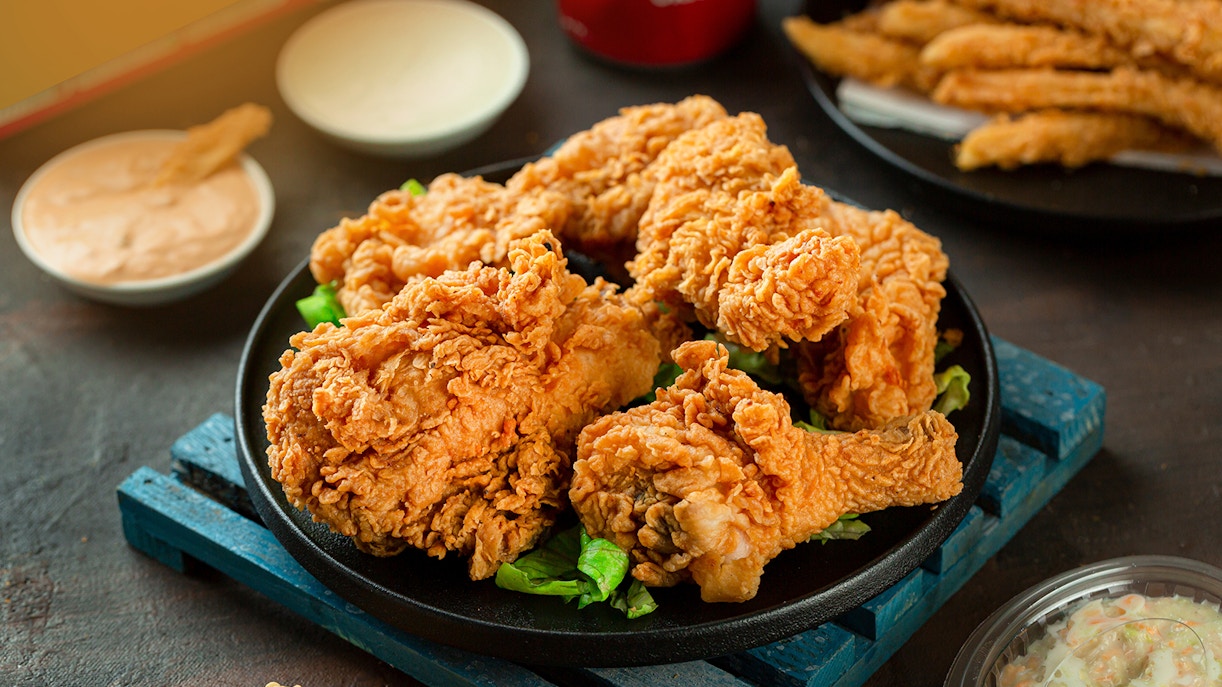 Fried chicken pieces on a plate with dipping sauces and coleslaw.