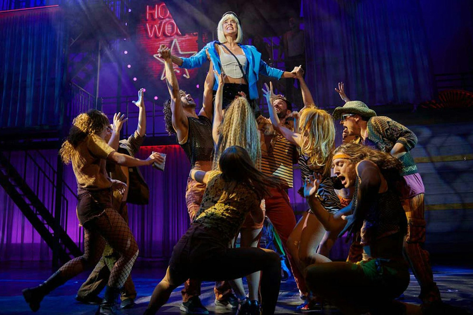 Performers on stage during "Pretty Woman - El musical" with vibrant lighting and choreography.