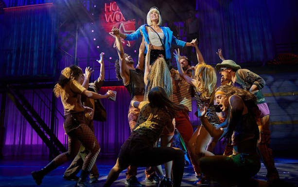 Performers on stage during "Pretty Woman - El musical" with vibrant lighting and choreography.