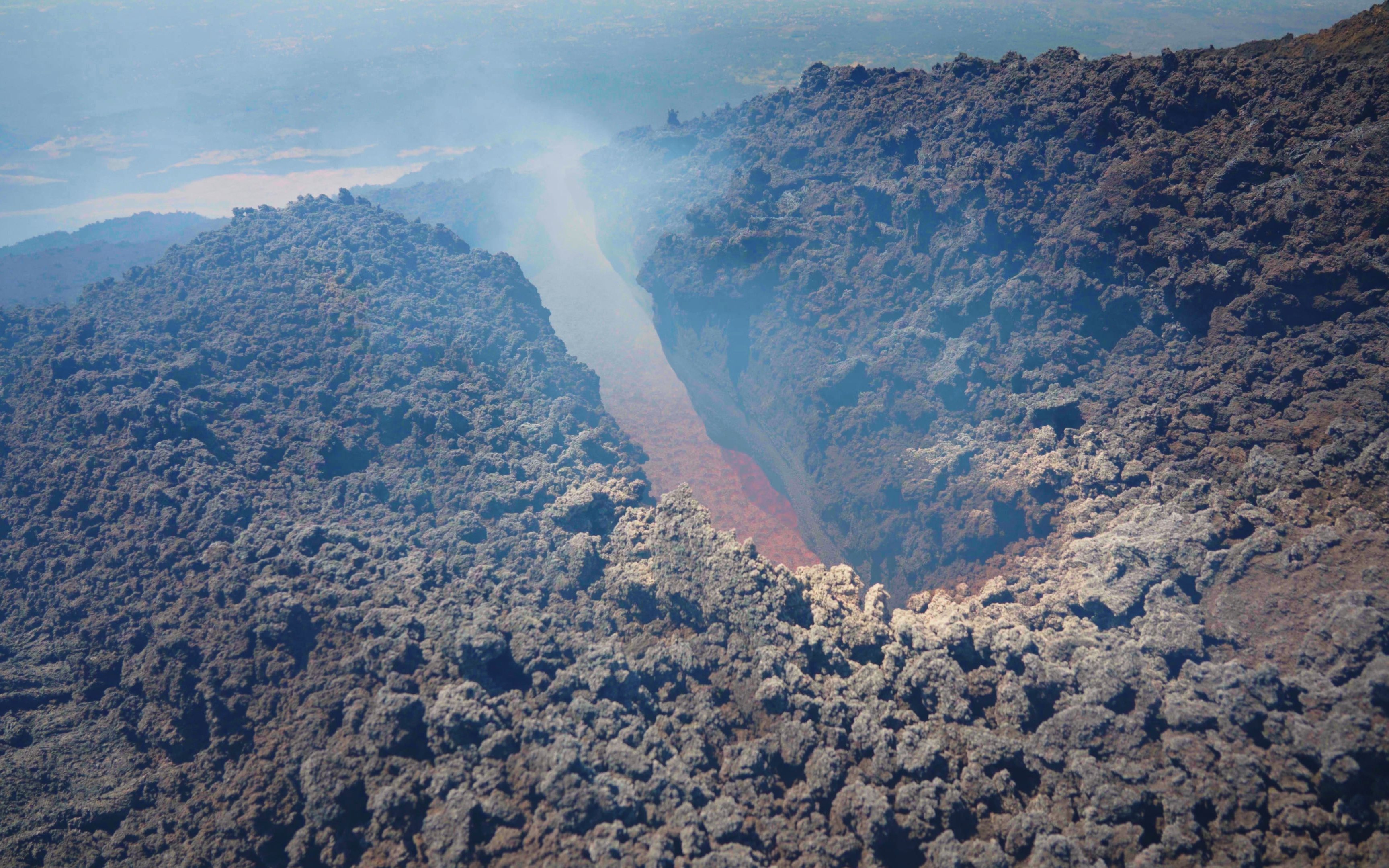 Aerial view of Mount Etna's volcanic crater with visible lava flow.