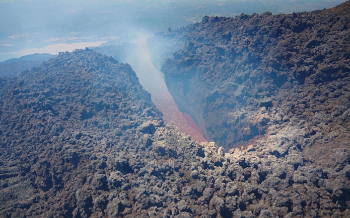 Aerial view of Mount Etna's volcanic crater with visible lava flow.