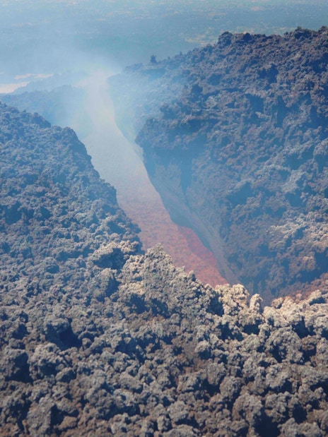 Aerial view of Mount Etna's volcanic crater with visible lava flow.