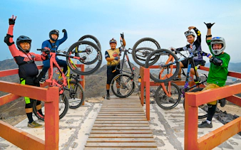 Group of cyclists holding mountain bikes at Fujairah Adventure Park viewpoint.