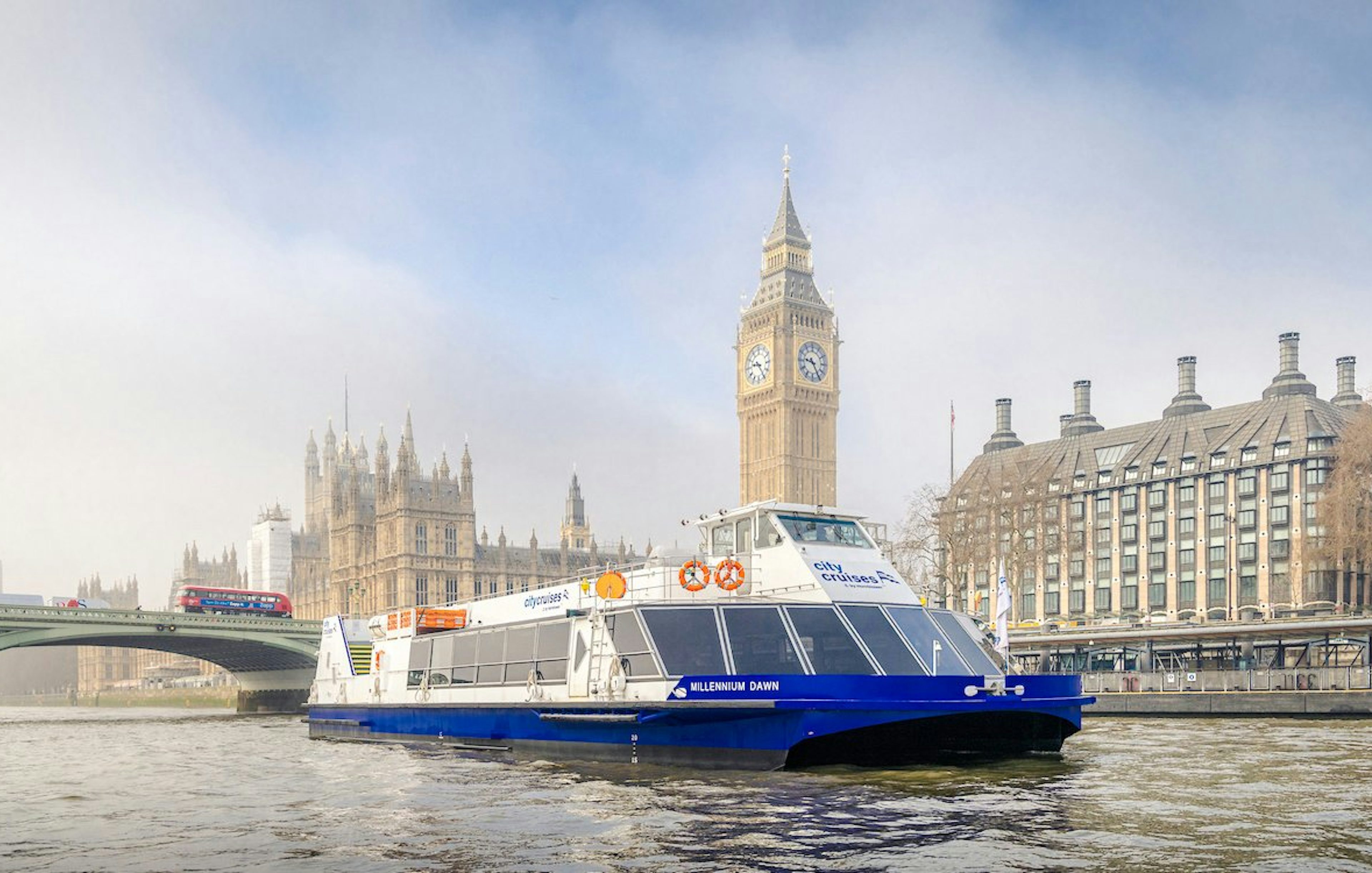 Cruise boat on Thames River with Big Ben and Westminster Bridge in London.