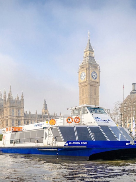 Cruise boat on Thames River with Big Ben and Westminster Bridge in London.