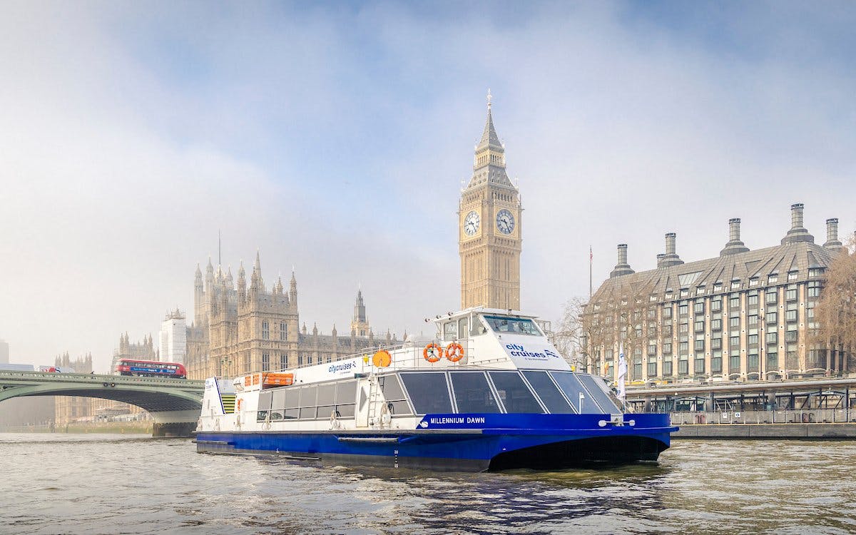 Cruise boat on Thames River with Big Ben and Westminster Bridge in London.