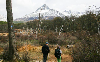 Hikers on trail with snow-capped mountains in Esmeralda Lake, Argentina.