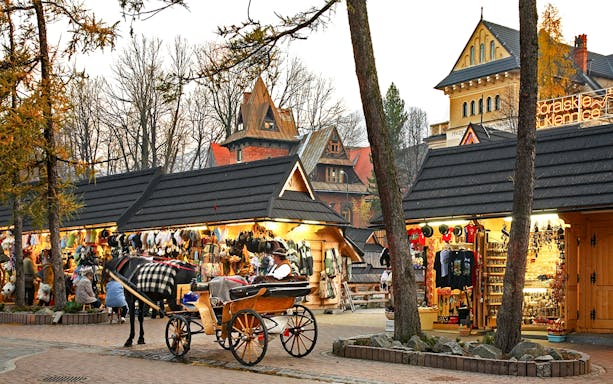 Horse-drawn carriage near market stalls in Zakopane, Poland, during Krakow day trip.
