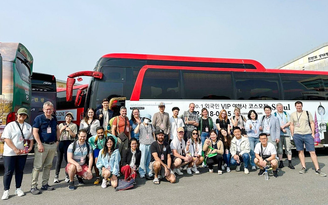Tour group posing in front of a red and black bus on a DMZ tour in South Korea.