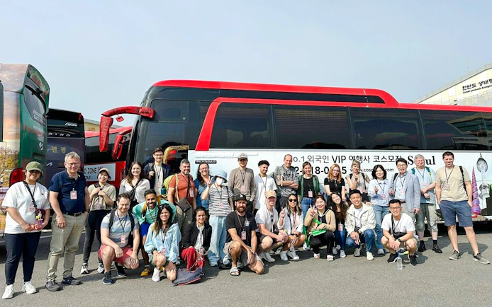 Tour group posing in front of a red and black bus on a DMZ tour in South Korea.