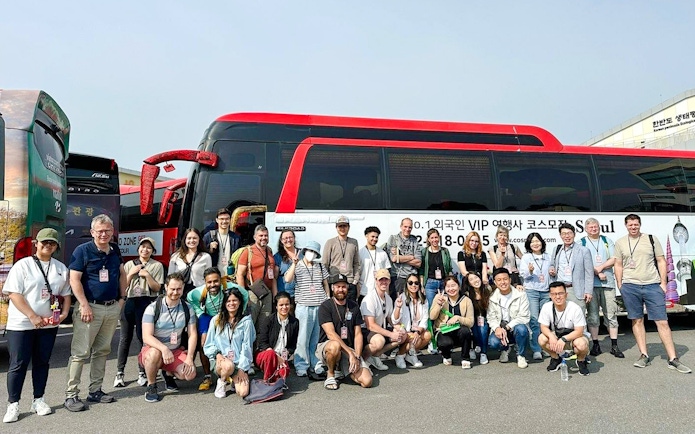 Tour group posing in front of a red and black bus on a DMZ tour in South Korea.