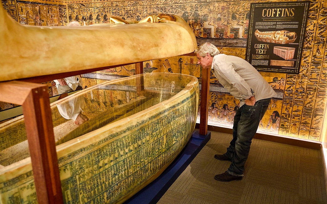 Visitor examines Egyptian sarcophagus at Tomb of the Pharaoh exhibit, Cairns.