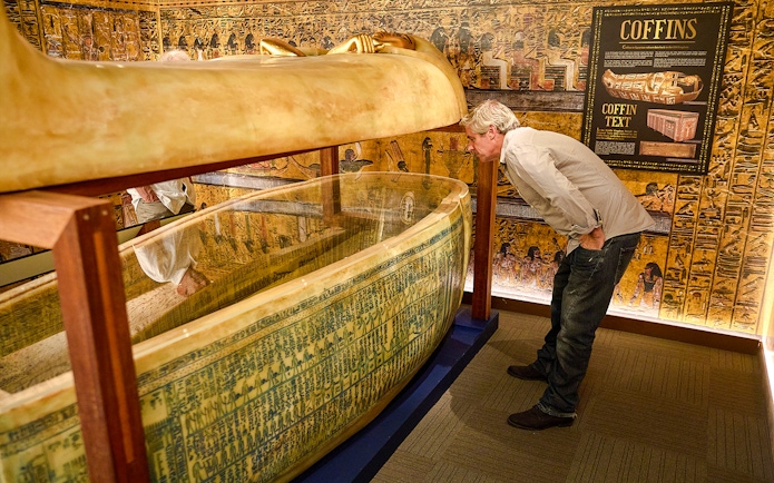 Visitor examines Egyptian sarcophagus at Tomb of the Pharaoh exhibit, Cairns.