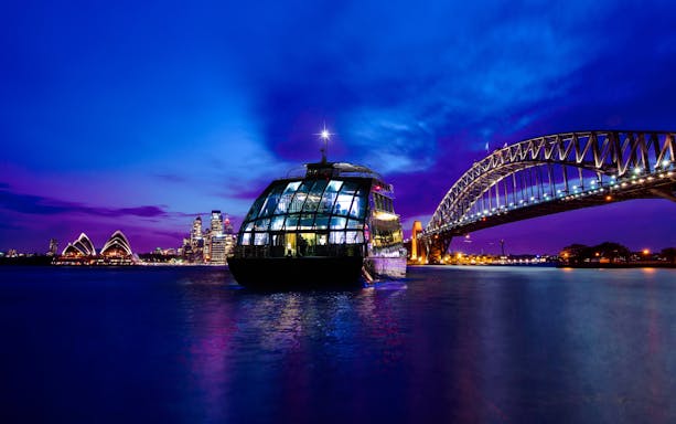 Cruise ship on Sydney Harbour with views of the Opera House and Harbour Bridge at night.