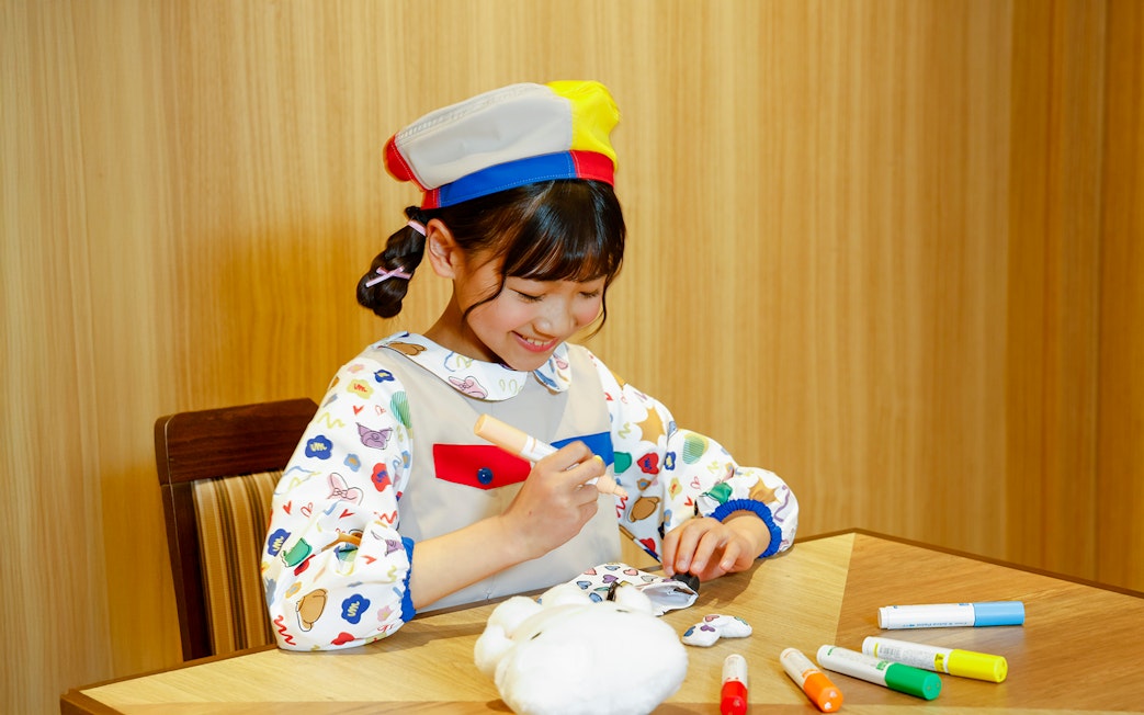 Child coloring a plush toy at Sanrio Puroland, Japan.