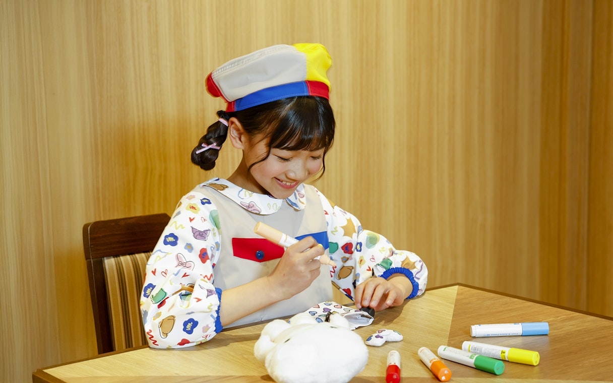 Child coloring a plush toy at Sanrio Puroland, Japan.