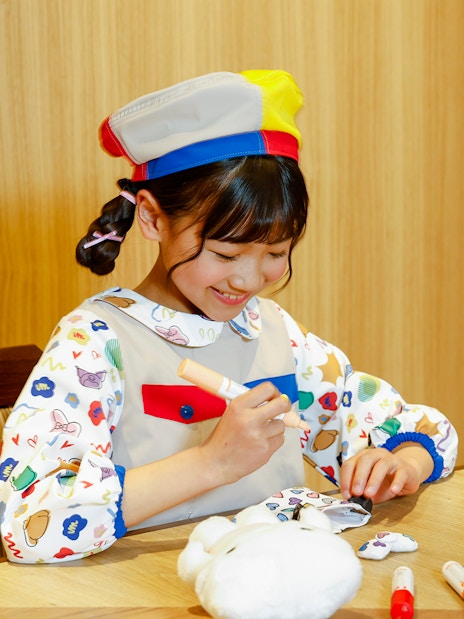 Child coloring a plush toy at Sanrio Puroland, Japan.