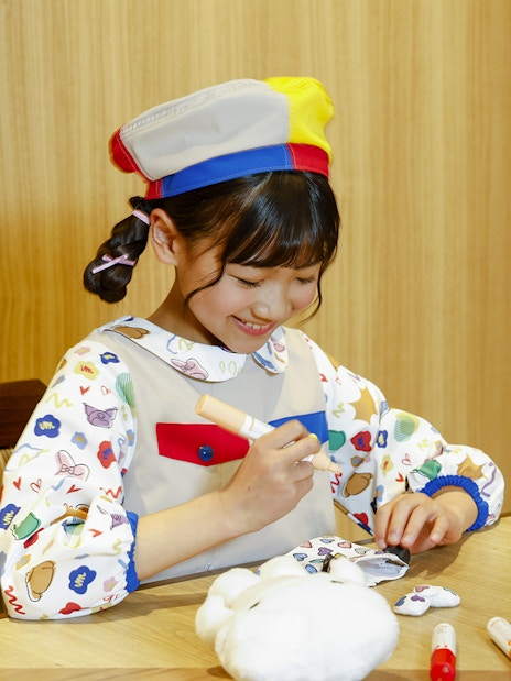 Child coloring a plush toy at Sanrio Puroland, Japan.