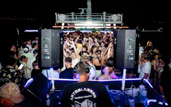 Crowd dancing on a night boat party in Split with live DJ and vibrant lights.