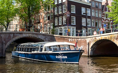Canal boat cruising under a bridge in Amsterdam.