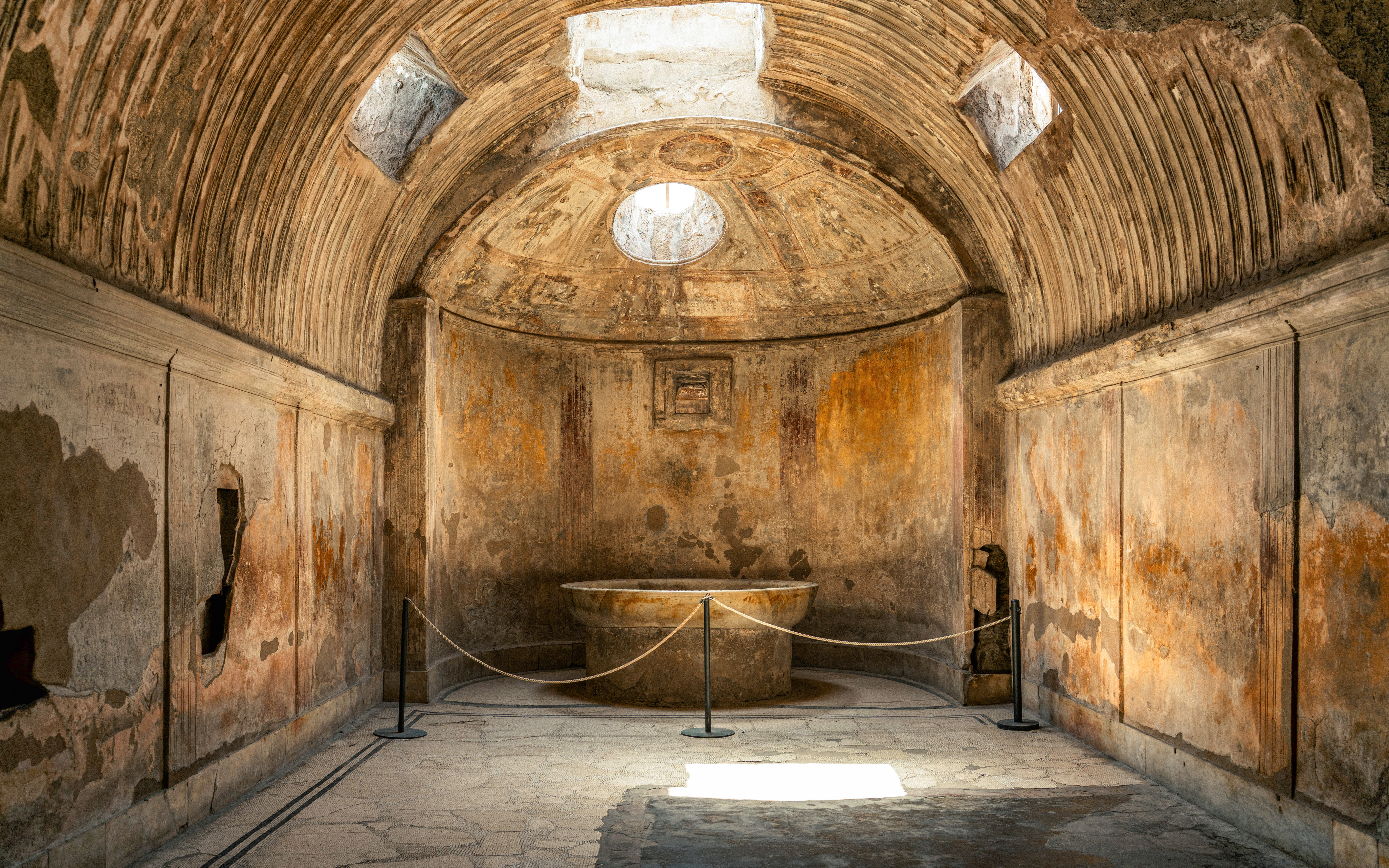Forum Baths interior in ancient Pompeii, Italy, showcasing a circular bath and arched ceiling.