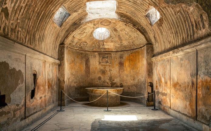 Forum Baths interior in ancient Pompeii, Italy, showcasing a circular bath and arched ceiling.
