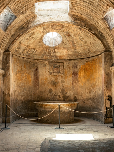 Forum Baths interior in ancient Pompeii, Italy, showcasing a circular bath and arched ceiling.