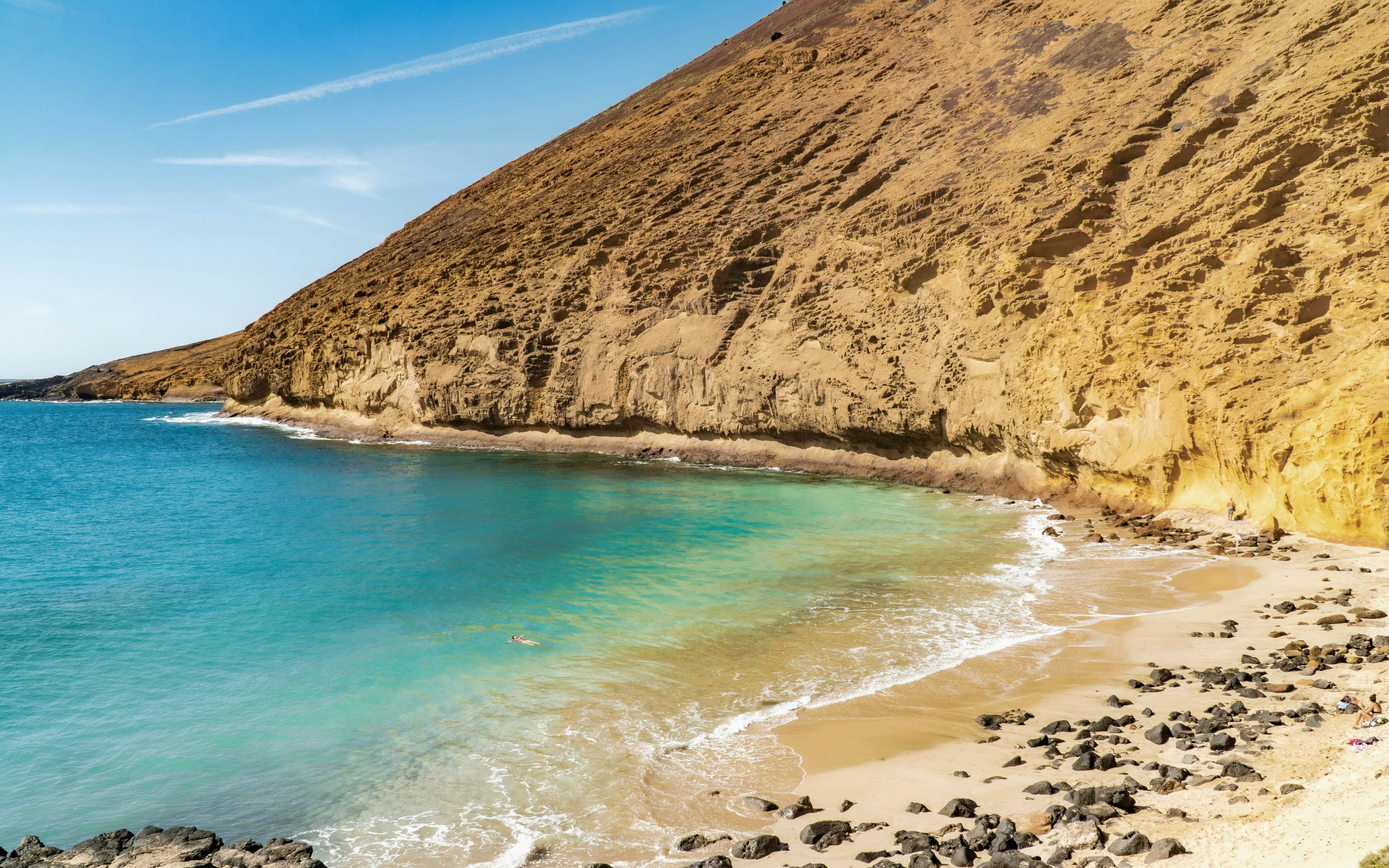 Montaña Amarilla beach with turquoise waters and rocky cliffs in Tenerife, Spain.