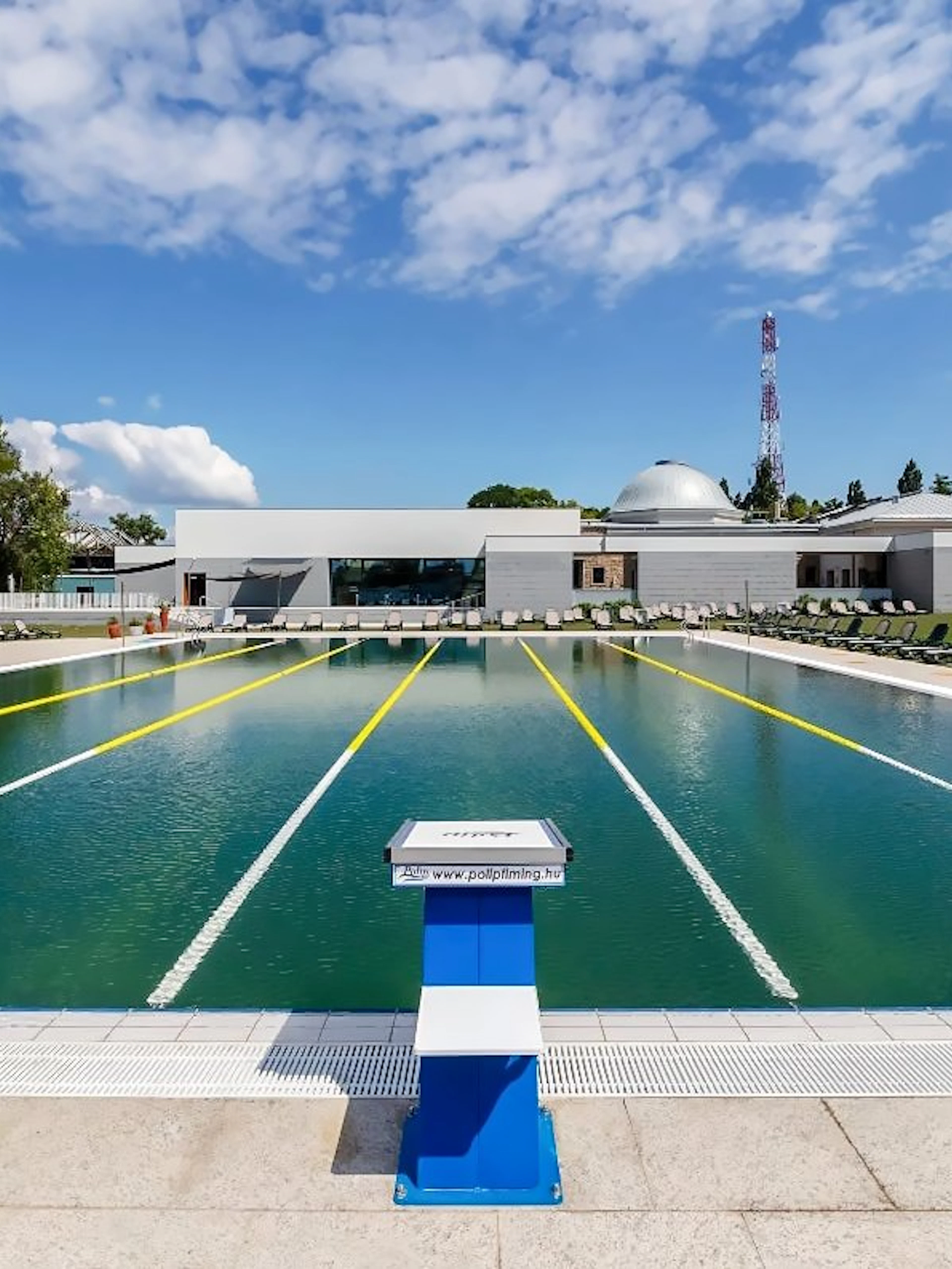 Outdoor pool at Pesterzsebet Bath, Budapest with diving boards and lounge chairs.