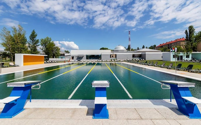 Outdoor pool at Pesterzsebet Bath, Budapest with diving boards and lounge chairs.