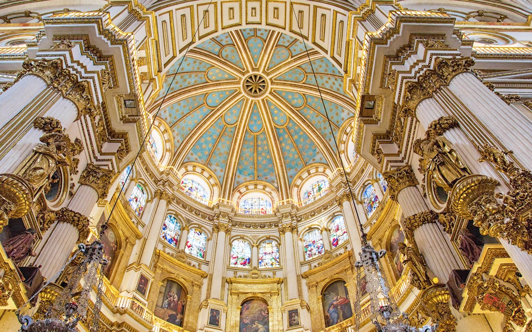 Granada Cathedral interior with ornate columns and stained glass windows.