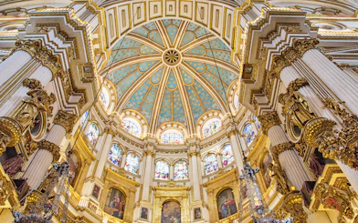 Granada Cathedral interior with ornate columns and stained glass windows.