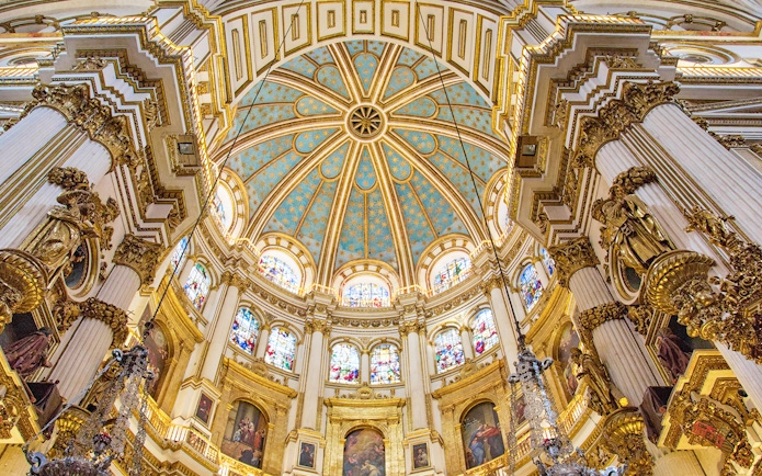 Granada Cathedral interior with ornate columns and stained glass windows.